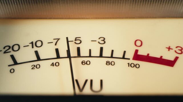 Analog dial indicator of audio signal level amplifier. Vintage arrow moves with sound level. Round classic volume indicator with yellow backlight, VU meters. Close-up of old measuring dB decibels