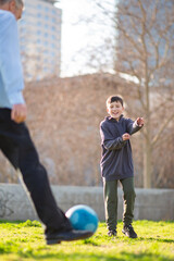 Naklejka premium Grandfather kicks soccer ball while smiling boy plays along