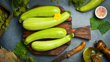 Green zucchini on a wooden cutting board, ready for cooking. Top view.