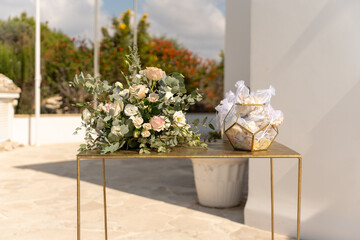 Elegant floral arrangement and gift display on a sunny outdoor patio surrounded by lush greenery...