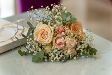 Delicate bouquet of pastel roses and greenery arranged on a smooth surface inside a bright and elegant venue