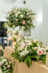 Elegant floral arrangements adorn a celebratory table at a vibrant wedding reception in a beautifully decorated venue