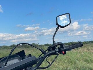 Motorcycle handlebar and mirror with blue sky reflection