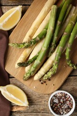 Different raw asparagus spears and spices on wooden table, flat lay