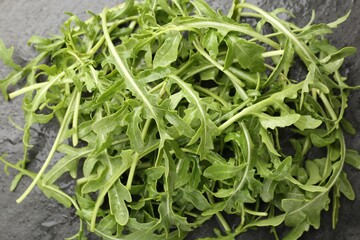 Fresh ripe green arugula leaves on black table, top view