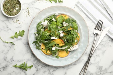 Tasty salad with arugula, cheese, peach, basil and spices on white marble table, flat lay