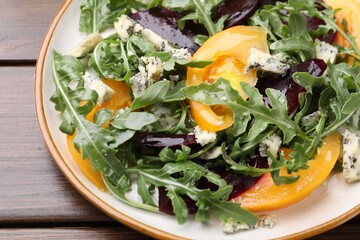 Tasty salad with arugula, blue cheese and vegetables on wooden table, closeup