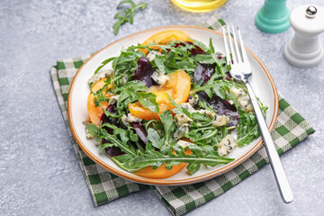 Tasty salad with arugula, blue cheese and vegetables on grey textured table, closeup