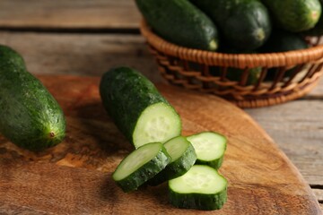 Cut and whole cucumbers on wooden table, closeup