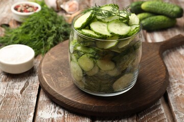 Making pickles. Slices of fresh cucumbers in open jar and dill on color wooden table, closeup