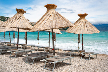 Neatly arranged sun loungers and straw umbrellas on the Adriatic coast of Baška. The turquoise...