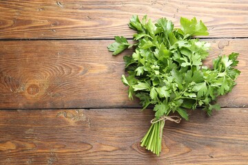 Bunch of fresh parsley on wooden table, top view. Space for text
