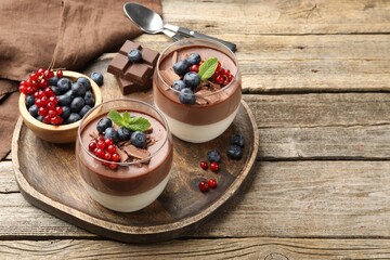 Delicious panna cotta with chocolate, berries and mint on wooden table, closeup. Space for text
