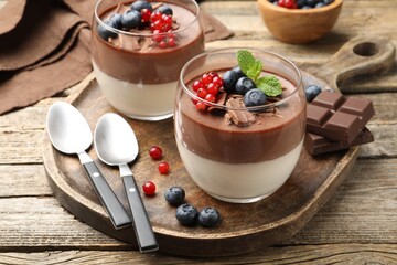 Delicious panna cotta with chocolate, berries and mint on wooden table, closeup