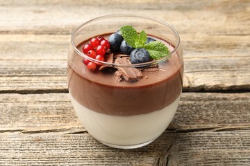 Delicious panna cotta with chocolate, berries and mint on wooden table, closeup