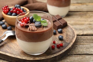 Delicious panna cotta with chocolate, berries and mint on wooden table, closeup