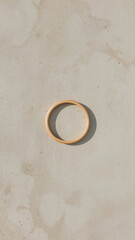 Simple Wooden Hoop Ring on a Textured Light Beige Surface with Shadows natural