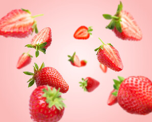 Yummy fresh strawberries swirling in air against pink background