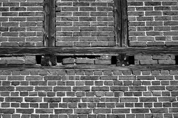 fragment of a historic half-timbered frame wall with wooden beams and red bricks