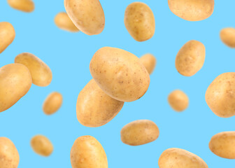 Raw potatoes in air against light blue background