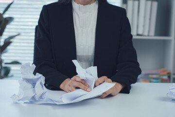 Frustration at the Desk: A professional in a business attire, crumples paper expressing the...
