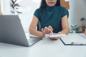 Focused Calculation at Desk: A focused professional meticulously calculates figures on a desk amidst a dynamic workplace. The scene captures a blend of productivity and precision.