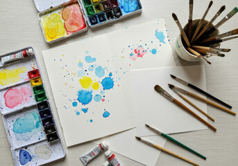 Watercolors and paint brushes laid out on a table.
