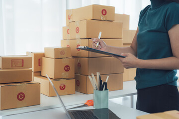 Online Order Fulfilment: A person meticulously manages and inspects a pile of parcels, using a clipboard in a logistics setup, showcasing the efficiency and precision of order processing.