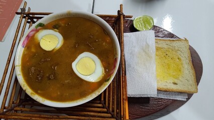 A bowl of hearty homemade beef and vegetable stew garnished with hard-boiled eggs, served with a...