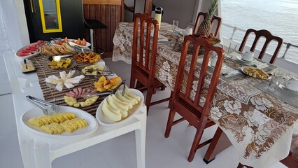 Delicious and abundant breakfast buffet with a variety of fresh tropical fruits, breads, and cheese served on the deck of a boat during a relaxing tour on the water. Leisure and travel concept.