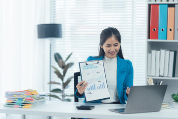 Businesswoman in a Virtual Meeting: An elegant businesswoman, in a modern office, demonstrates the efficiency of a presentation during a video conference using her laptop.