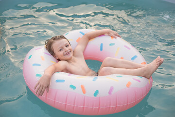 Boy Relaxing on a Donut Pool Float in the Water