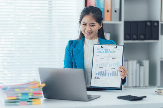 Online Business Presentation: A focused woman dressed in a blazer, is engaged in a video call while showcasing a detailed business report, revealing financial data in a bright and organized setting.