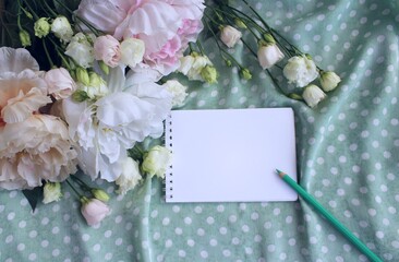 A notebook and a bouquet of peonies and eustoma in pastel colors. A greeting card.