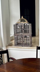 Antique inspired two-tier birdcage with golden detailing, ideal for home styling.