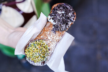 Young Italian woman holding a Italian street sweet cannoli in her hand