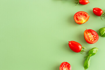 Fresh red tomatoes scattered with basil on pastel surface