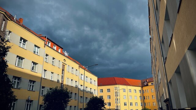 the old town .Residential four-story yellow-headed buildings with gray color and brown roof in Europe against cloudy sky before rain - Powered by Adobe