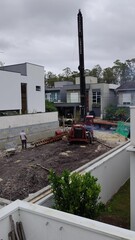 High-angle view of a residential construction site with a large auger drilling rig preparing the...