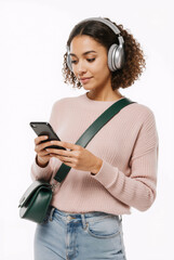 Girl with curly brown hair Listening to songs in headphone and looking over phone