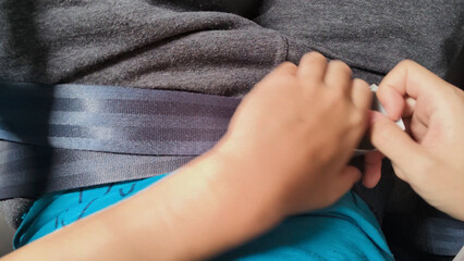 Close-up point of view shot of a person's hands releasing the seatbelt, lift the buckle flap during flight. Passenger preparing to leave the plane. Travel safety concept.