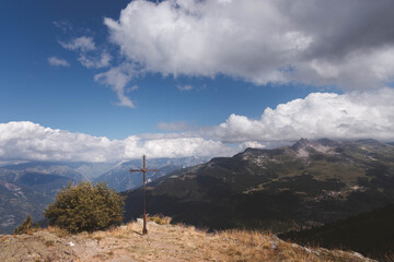 Rustic metal summit cross overlooking vast mountainous horizon