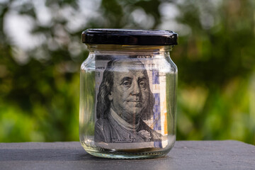 US dollar banknote saving money in glass jar. Consumption and economy