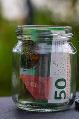 Swiss franc CHF banknote saving money in glass jar. Consumption and economy