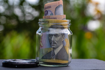 Romanian LEI banknote saving money in glass jar. Consumption and economy