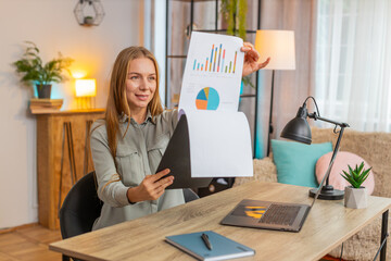 Happy mature businesswoman freelancer working with documents from home office, analyzing...