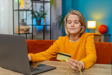 Caucasian teenager boy making an online purchase on laptop at home. Entering credit card...