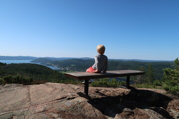 Young boy on a bench enjoying view over the coastline at Swedens Höga Kusten