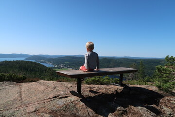 Young boy on a bench enjoying view over the coastline at Swedens Höga Kusten