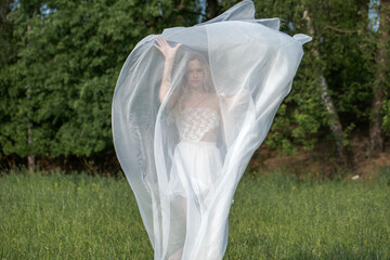 Sexy beautiful blonde girl posing with transparent fabric